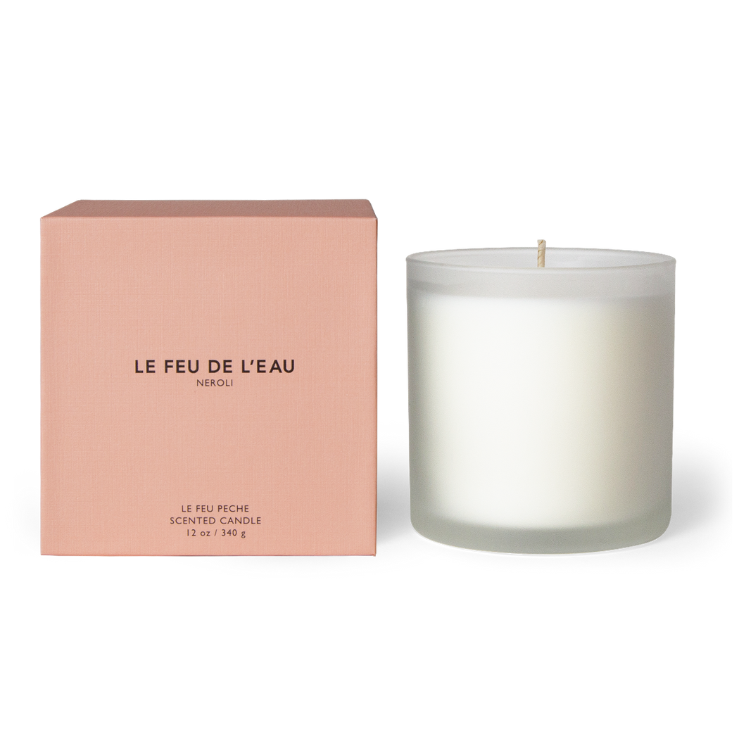 Indulge in the 12oz Fleur candle, blending Bitter Orange, Mandarin, Orange Blossom, and Tonka Bean in Apricot and Coconut wax. With lead-free cotton wicks and a burn time of 65 hours, each candle brings a touch of artisanal luxury. Made in Los Angeles by LE FEU DE L'EAU and packaged in unique linen-textured paper. The candle is displayed unboxed, positioned beside its packaging, set against a clean white backdrop. Made in Los Angeles by LE FEU DE L'EAU.