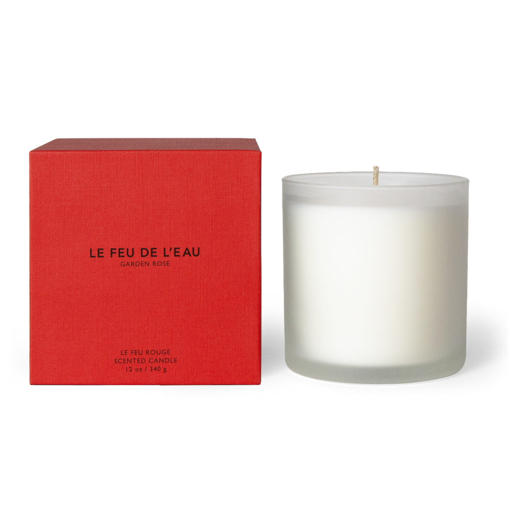 Indulge in the 12oz Rouge candle, blending red rose, Moroccan rose, and white rose in Apricot and Coconut wax. With lead-free cotton wicks and a burn time of 65 hours, each candle brings a touch of artisanal luxury. Made in Los Angeles by LE FEU DE L'EAU and packaged in unique linen-textured paper. Shop the collection. The candle is displayed unboxed, positioned beside its packaging, set against a clean white backdrop.