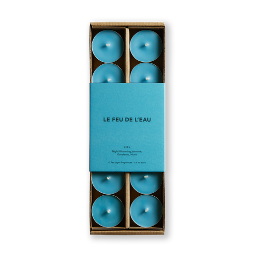 Experience the allure of Ciel scented tea light candles by Le Feu De L'eau. Enriched with Night Blooming Jasmine, Gardenia, and Musk, these hand-poured treasures evoke romance and serenity. Crafted in LA with natural ingredients. Paraben free and no preservatives. Set of 12 | .5oz Tea Lights. Image is of blue colored tea light candles in matching blue colored packaging. 