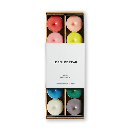 Discover the essence of Le Feu De L'eau scented rainbow tea light candles, featuring all 12 fragrances from the Artisanal Collection. Each set meticulously poured in small batches in Los Angeles, crafted with cruelty-free coconut apricot wax and natural fragrance. Clean burn, lead-free wicks. Paraben-free.  Image of colored tea light candles in box with white packaging. 