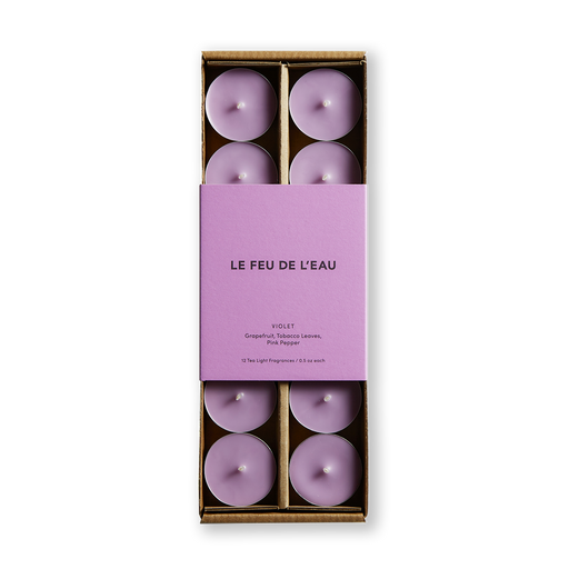Indulge your senses with Violet scented tea light candles by Le Feu de L'eau, blending grapefruit, tobacco leaves, and pink pepper. Experience a rich fusion of leather, smoked tobacco leaves, and invigorating grapefruit. Set of 12 cruelty-free, coconut apricot wax, and natural fragrance tealights. Natural fragrance. Image of purple colored tea lights in box with matching colored purple packaging.