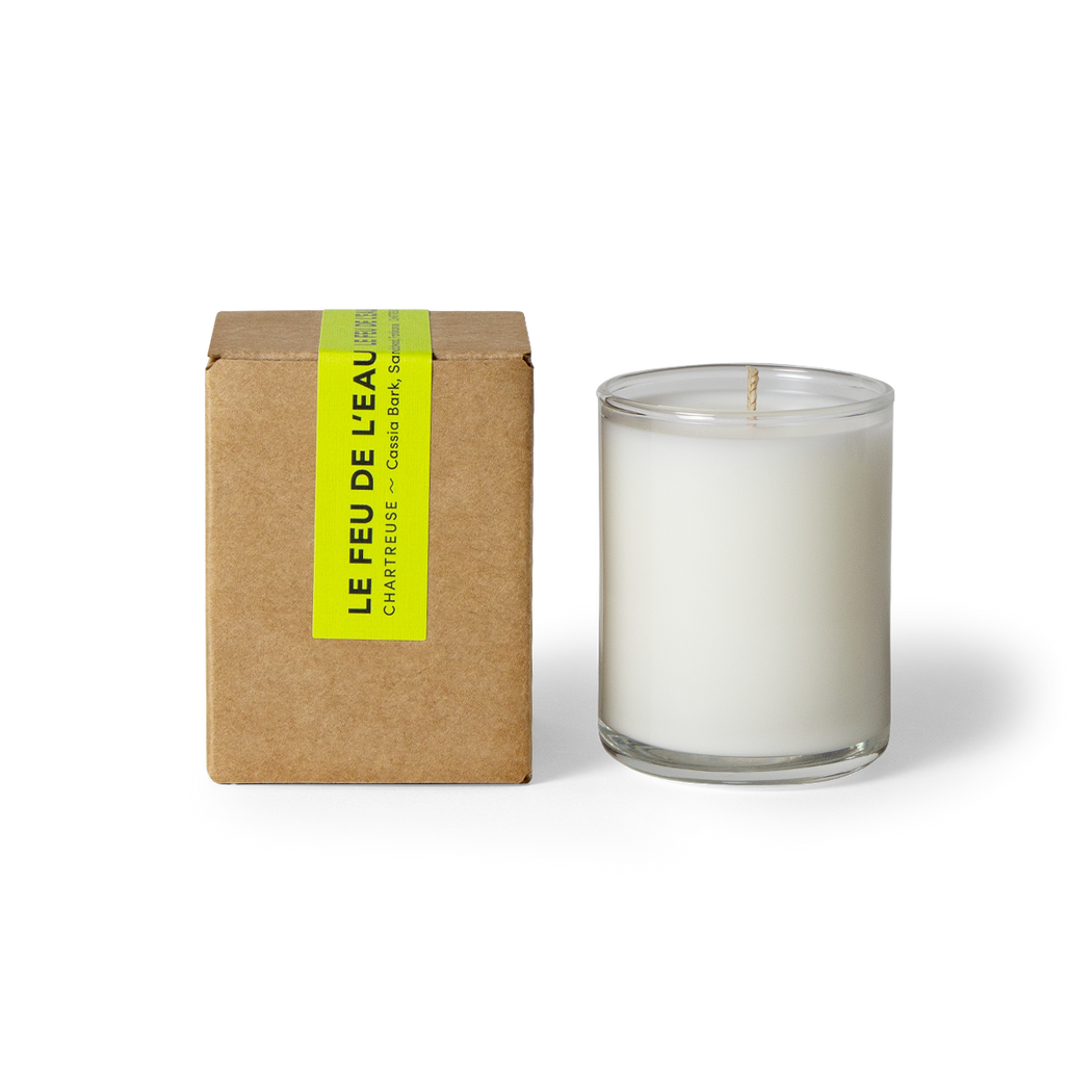 Experience the 3oz Chartreuse glass candle, blending Cassia Bark, Sandalwood, and Frankincense- three kingly scents commingle for mystical moments of transition and delight. Hand-poured in LA, cruelty-free, with coconut apricot wax, natural fragrance, and lead-free cotton wicks. No harmful additives. The candle is displayed unboxed, positioned beside its packaging, set against a clean white backdrop.