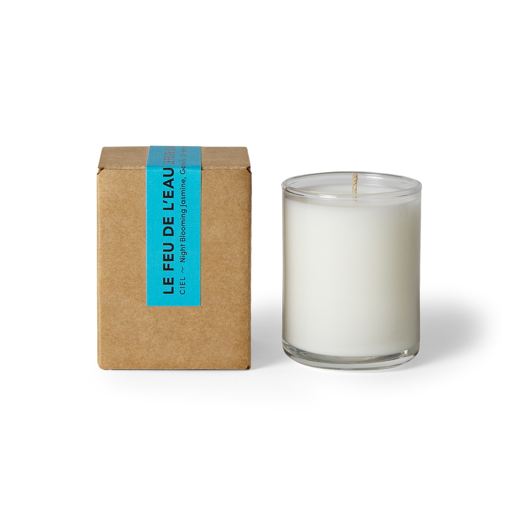  Indulge in the 3oz Ciel glass candle, blending night blooming jasmine, gardenia and musk. Hand-poured in LA, cruelty-free, with coconut apricot wax, natural fragrance, and lead-free cotton wicks. No harmful additives. The candle is displayed unboxed, positioned beside its packaging, set against a clean white backdrop.